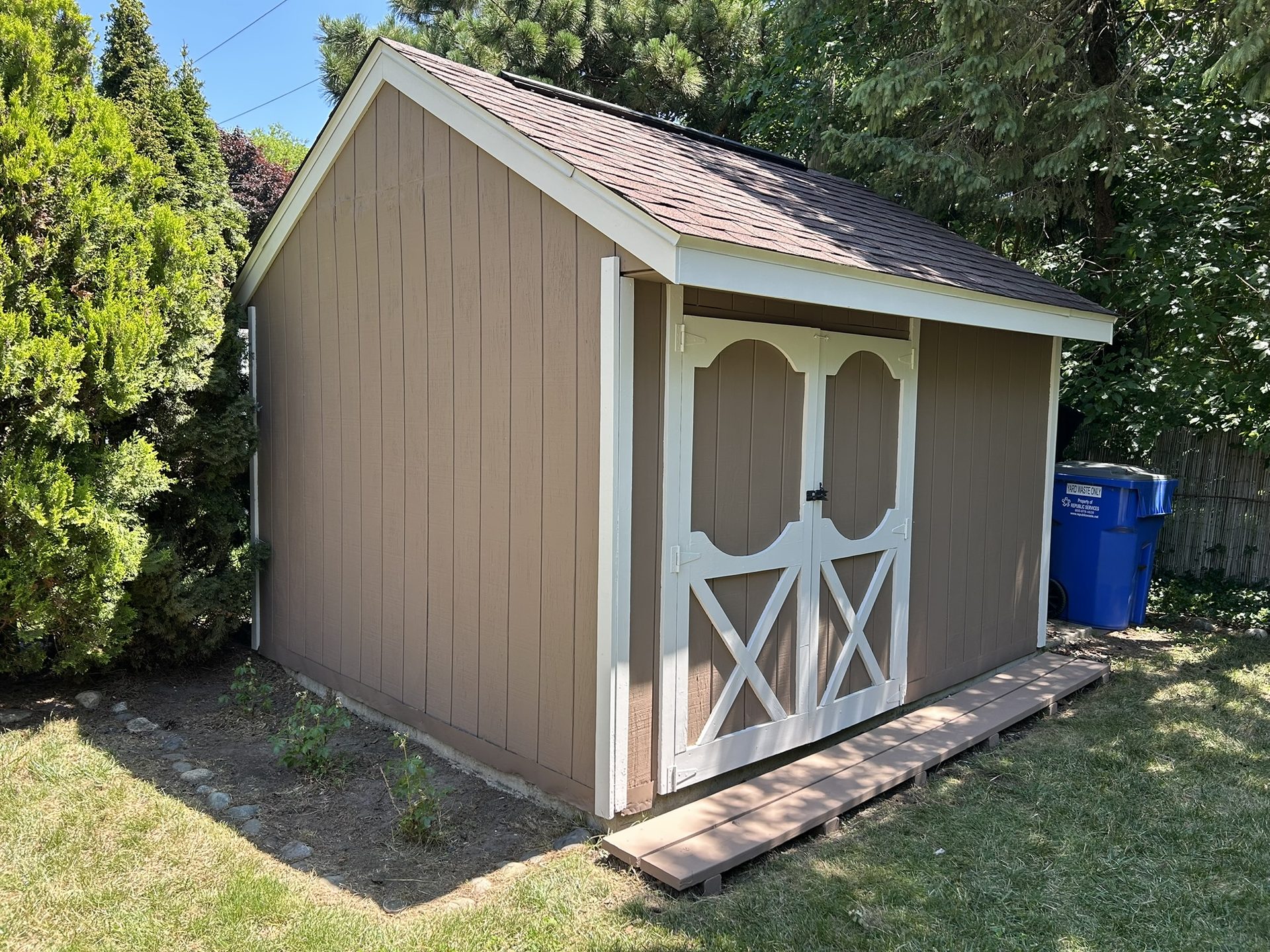 After: the same shed repainted brown with white trim and doors