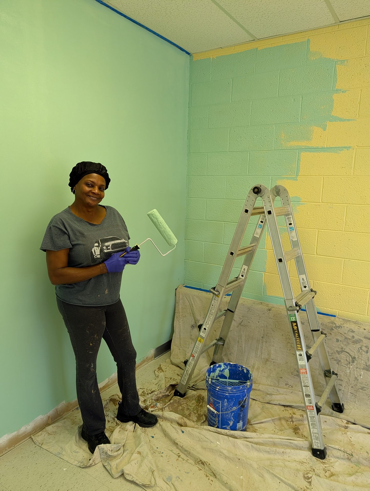 Crew member cutting in a freshly rolled green interior wall with a brush