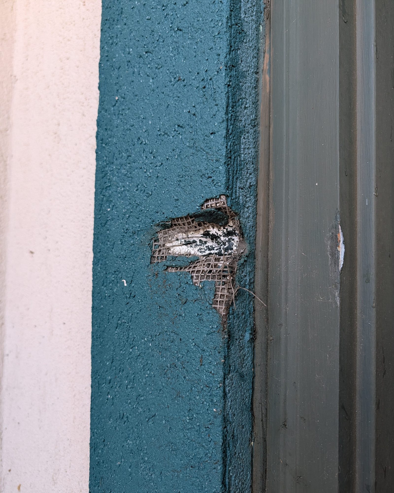 Before: stucco window surround with a hole punched through to the mesh